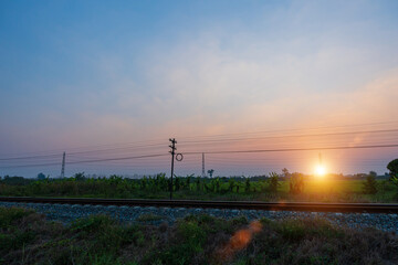 View of railway tracks in a rural scene during sunset sky.
