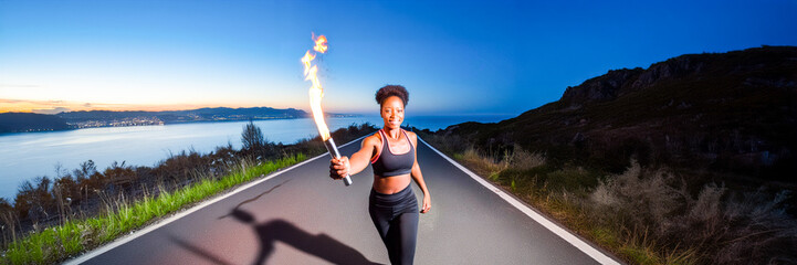 running woman with a torch on road by the sea in the evening