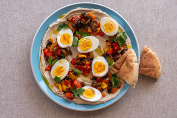 Traditional Israeli Sabich Salad including boiled eggs, grilled eggplant, chopped vegetables, tahini sauce.