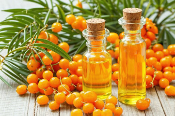Essential oil and branch of sea-buckthorn with berries and leaves