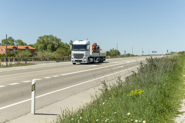 Fototapeta na wymiar A tractor truck driving with an empty trailer with integrated crane