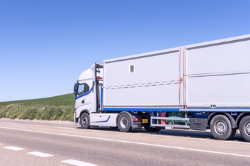 modern truck driving with a trailer with prefabricated construction sheds on a country road