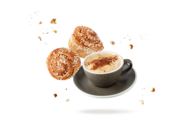 Cup hot cappucino coffee and fresh baked cinnamon buns with crumbs and sugar pieces flying falling  isolated on white