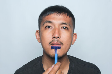 Asian young man being cut off beard and mustache isolated on white background.