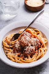 Spaghetti with meatballs, tomato sauce and parmesan on gray background