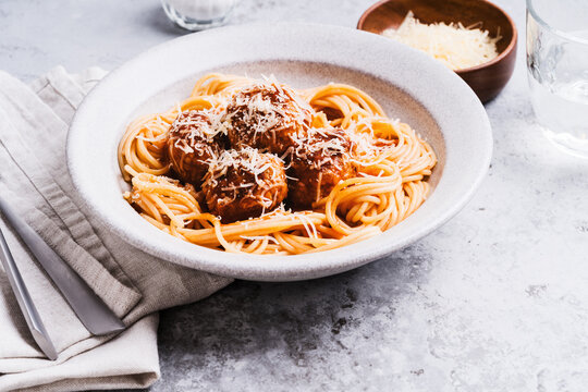 Spaghetti with meatballs, tomato sauce and parmesan on gray background