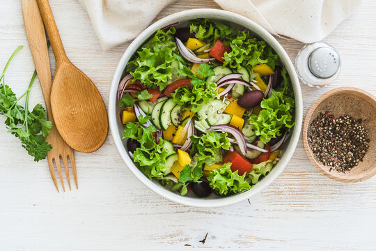 Bowl of fresh salad with vegetables on white wood rustic background