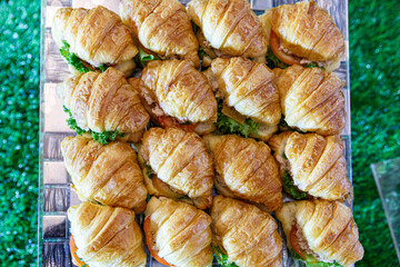 croissants cut and filled with tuna, egg and vegetables on a party platter.