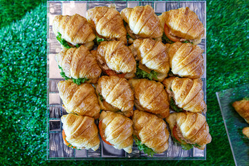 croissants cut and filled with tuna, egg and vegetables on a party platter.