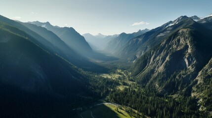 Aerial view of towering mountains with rugged cliffs and a valley below, sprinkled with evergreen...