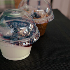 Blueberry trifle. Jelly with blueberries in plastic packaging. Dessert from mascarpone or ricotta cheese, blueberries and biscuit in glass on a dark concrete background.