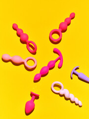 Bright sex toys background. anal plugs and dildo over yellow paper backdrop
