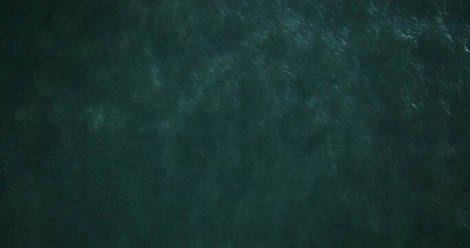 Directly above zoom out drone footage of vast seascape at beach during daytime