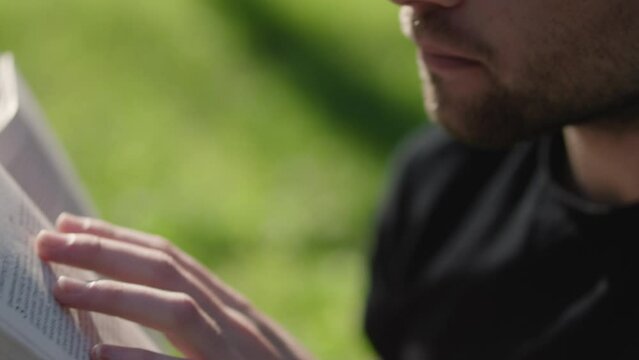 Young man reading his Bible outside on a warm sunny day