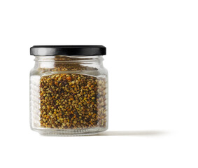 Bee pollen granules in a glass jar, on white background