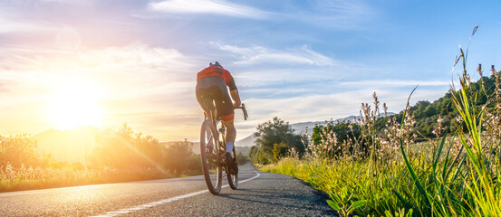 Mature Adult on a racing bike climbing the hill at mediterranean sea landscape coastal mountain...
