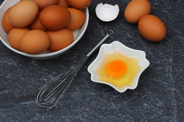 Brown eggs with a cracked egg in a bowl.