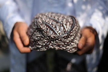 close up of a man's hand holding a headgear from West Java