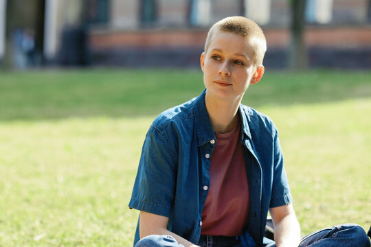 Female freshman androgynous sitting green area 