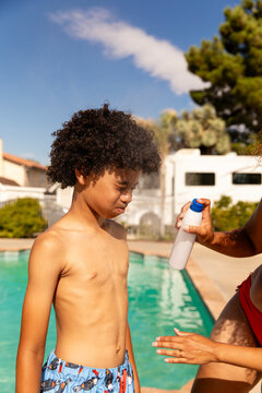 Pre-Teen Boy Closes Eyes And Mouth While Mother Applies Sunscreen