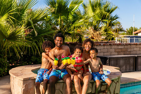 Fun Family On Vacation Cheers Their Pineapple Cups Near The Pool