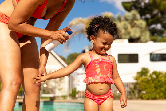 Woman Sprays Sunscreen On Child