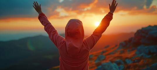 A young woman in a hoodie celebrates success at sunset on a mountain peak, captured in a panoramic banner with raised arms. - Powered by Adobe