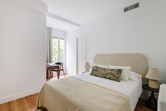 Simple and cozy room with white walls and a large double bed 