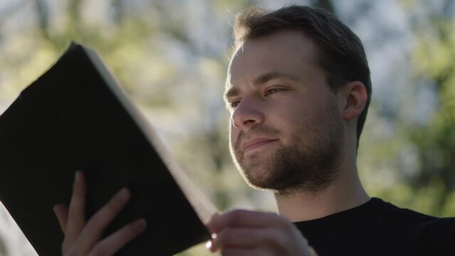 Young man reading his Bible outside on a warm sunny day