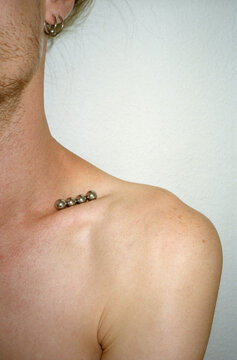 Close-up of pierced ear and neck with small metal balls