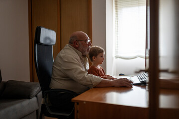 Boy with his grandfather using computer