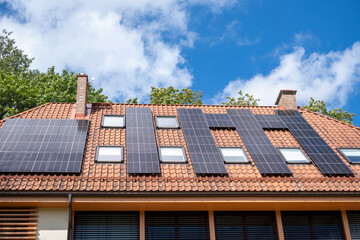 Solar panels line the roof of a suburban home, a testament to sustainable living and renewable energy trends, under a clear blue sky.