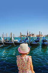 Little girl is watching the gondolas of the Grand Canal on a sunny day in Venice, Italy. San...