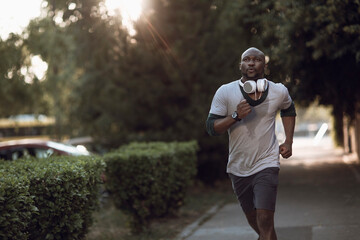 Active young black man jogging on the street