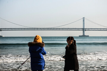 View of the tourists on the beach against the suspension bridge