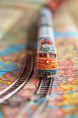 Fototapeta premium Close-up of a toy model train traveling on a paper map. Creative concept of land travel by railroad.