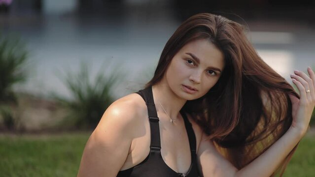 Luxurious, athletic woman, model posing on a green lawn in a contrasting, beautiful golden light. Attractive body and skin, model posing, confidence and femininity, sporty, rich life, love, gorgeous