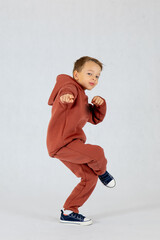 Little boy in hip hop dance position.Little boy model. Little boy in brown tracksuit on white background.
