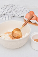 Home kitchen interior.Bowl with dough and measuring spoon, eggs and bowl of sugar on kitchen table in modern kitchen.