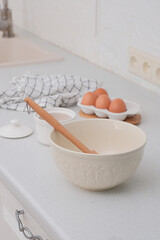 Home kitchen interior.Bowl with dough and spatula, eggs and bowl of sugar on kitchen table in modern kitchen.
