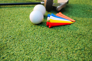 Colorful golf balls, clubs and tees lay on the green grass.