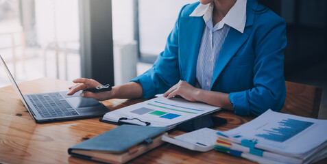 Asian Business woman using calculator and laptop for doing math finance on an office desk, tax,...