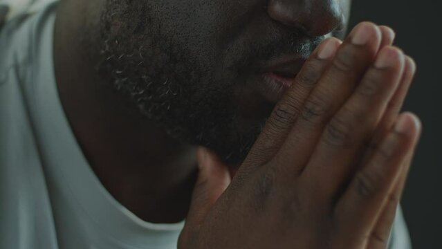 Close-up view of African American man holding hands together and saying grace while praying