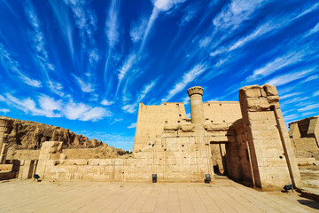 Beautiful bright blue skies and wispy cloud patterns over the atmospheric temple of Kom Ombo dedicated to crocodile goddess Sobek and Haroeris built by Ptolemy pharoahs in Kom Ombo,Near Aswan,Egypt - obrazy, fototapety, plakaty