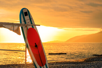 A surfboard is leaning against a pole on a beach