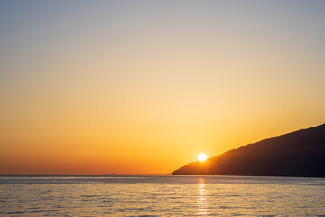 The sun is setting over the ocean, casting a warm glow over the water