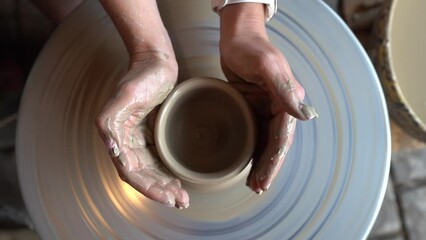 Dobele, Latvia- August 18, 2023 - Potter making ceramic pot on the twisted pottery wheel. Top view. Potter at work, close up. Handmade, craft. White clay. Slow motion