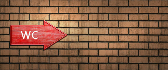 Red wooden shooter sign with the inscription WC hangs on a dark brick wall. Right arrow pointer