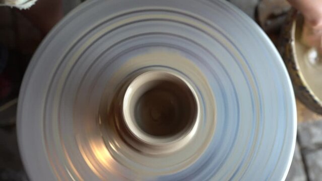 Dobele, Latvia- August 18, 2023 - Potter making ceramic pot on the twisted pottery wheel. Top view. Potter at work, close up. Handmade, craft. White clay. Slow motion