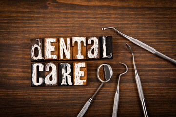DENTAL CARE. Alphabet blocks and metal doctor tools on wood texture background